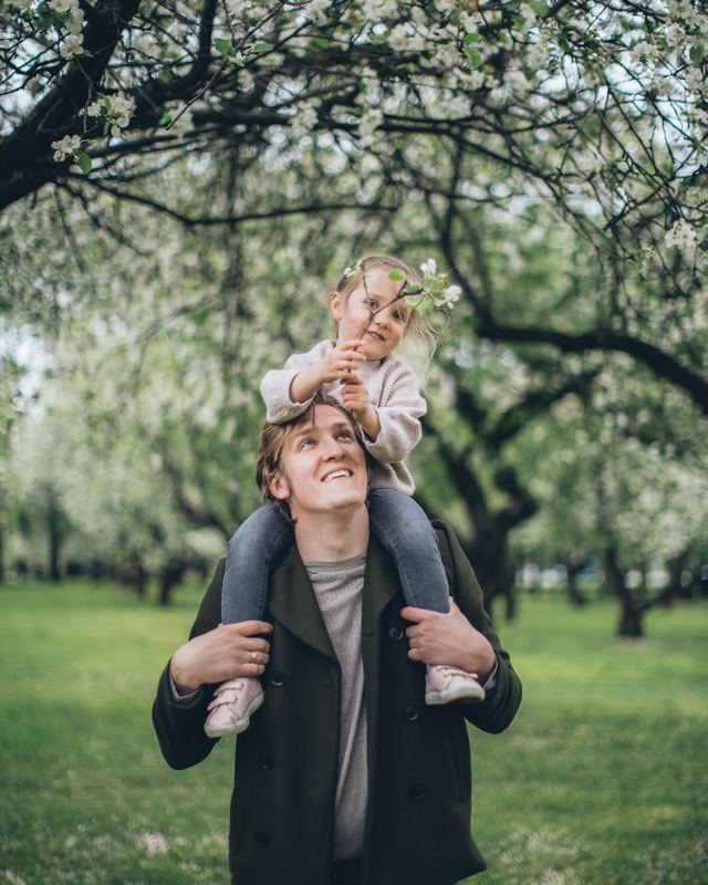 Pai carregando a filha nos ombros em um parque